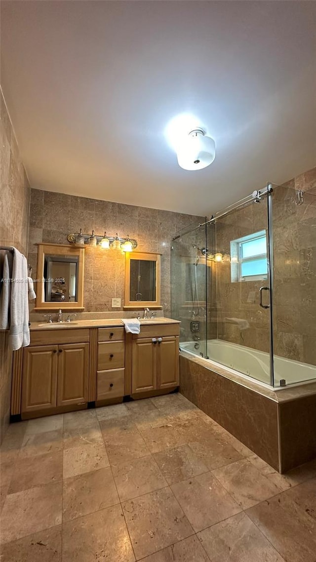 full bath with tile walls, a sink, tiled shower / bath, and double vanity