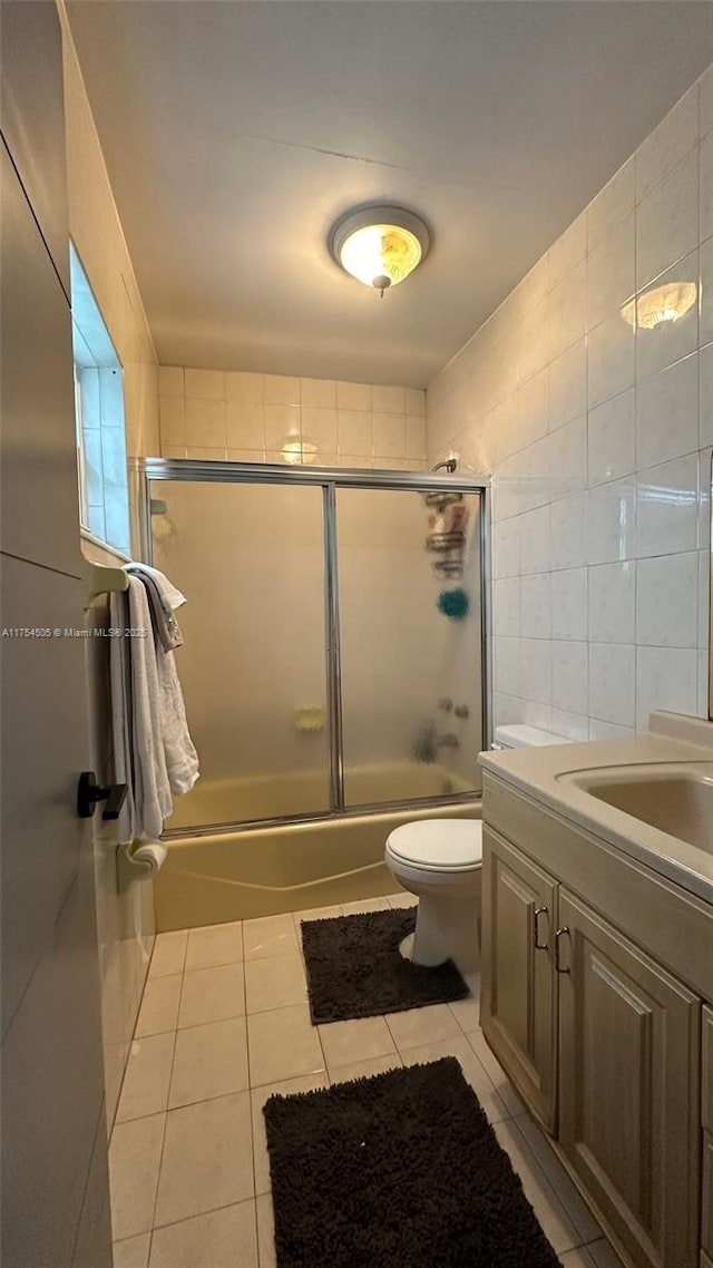 full bathroom featuring shower / bath combination with glass door, vanity, tile walls, and tile patterned floors