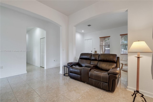 living room featuring visible vents, arched walkways, baseboards, and light tile patterned flooring