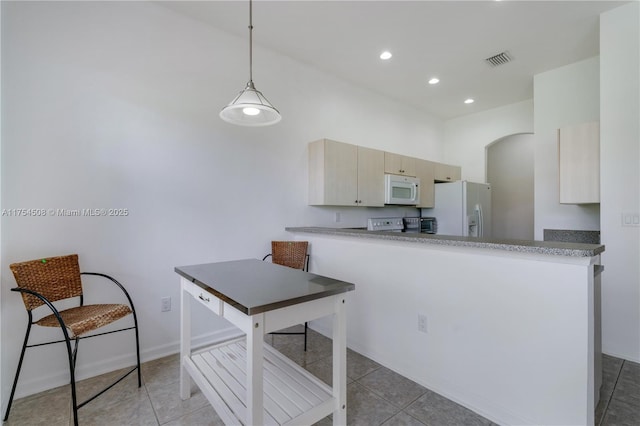 kitchen with arched walkways, light tile patterned flooring, a peninsula, white appliances, and visible vents