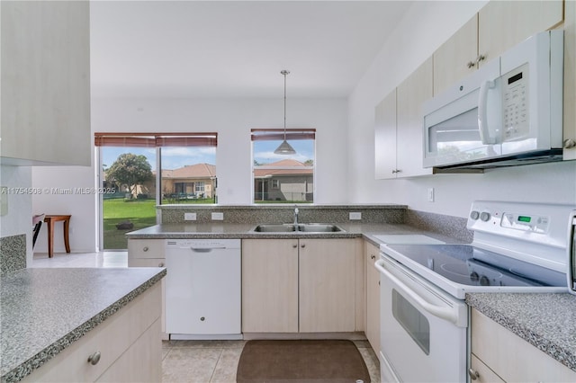 kitchen featuring light tile patterned flooring, a peninsula, white appliances, a sink, and hanging light fixtures