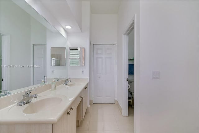 bathroom with double vanity, tile patterned flooring, a closet, and a sink