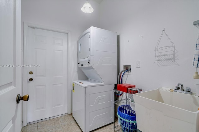 laundry room featuring stacked washer and dryer, light tile patterned floors, laundry area, and a sink