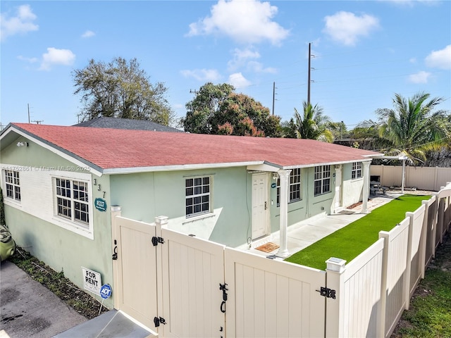 view of front facade featuring a fenced backyard, roof with shingles, and stucco siding