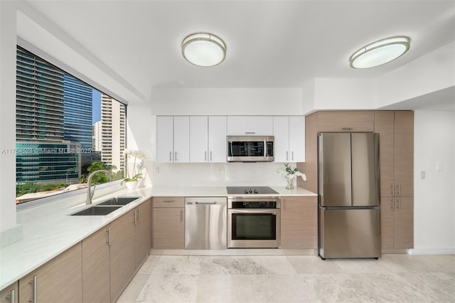 kitchen featuring appliances with stainless steel finishes, light countertops, a sink, and modern cabinets