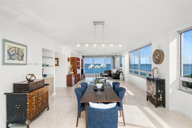 dining space featuring built in features, baseboards, and track lighting