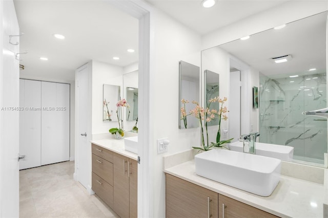 full bath with recessed lighting, two vanities, a sink, and a marble finish shower