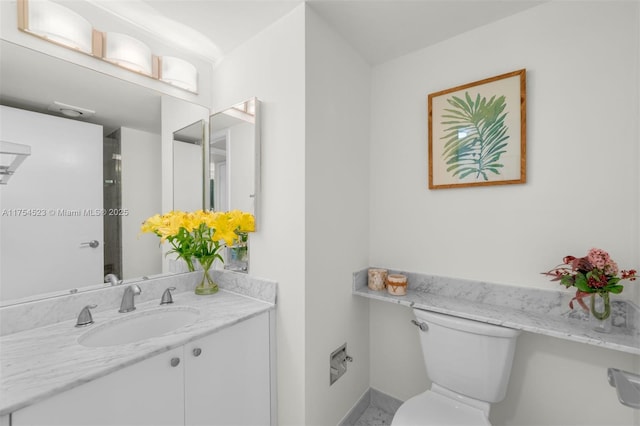 bathroom featuring baseboards, vanity, and toilet