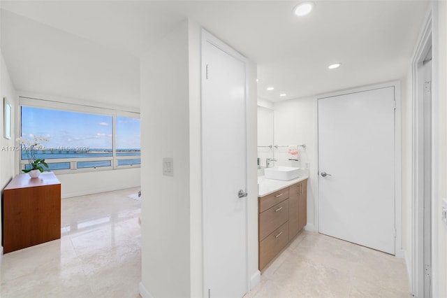 bathroom featuring a water view, recessed lighting, baseboards, and vanity