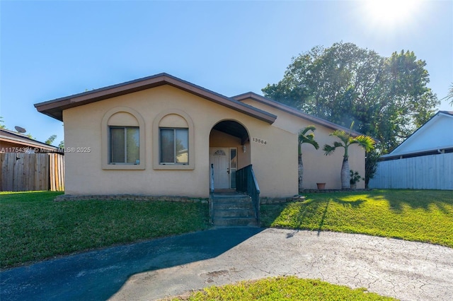 view of front of house featuring a front yard, fence, and stucco siding