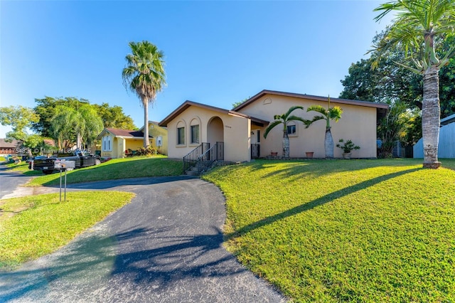 view of front facade with aphalt driveway, a front yard, and stucco siding