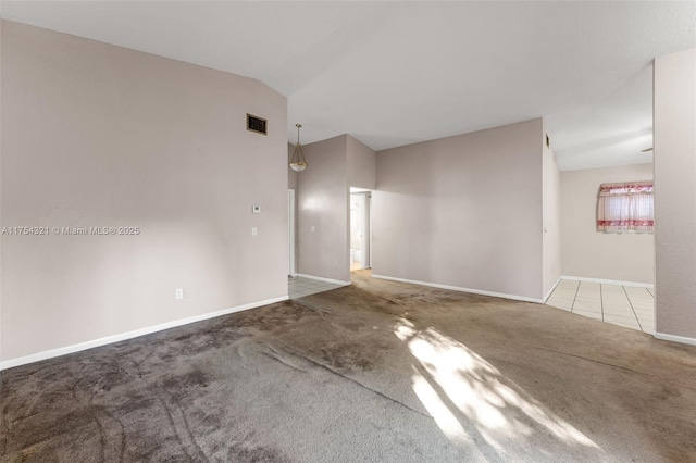 tiled spare room with lofted ceiling, carpet flooring, visible vents, and baseboards