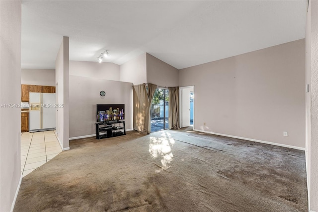 unfurnished living room with light carpet, light tile patterned floors, vaulted ceiling, and baseboards