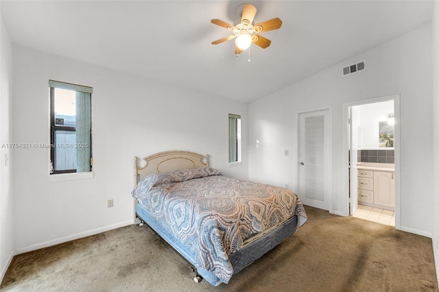 carpeted bedroom with baseboards, visible vents, a ceiling fan, connected bathroom, and vaulted ceiling