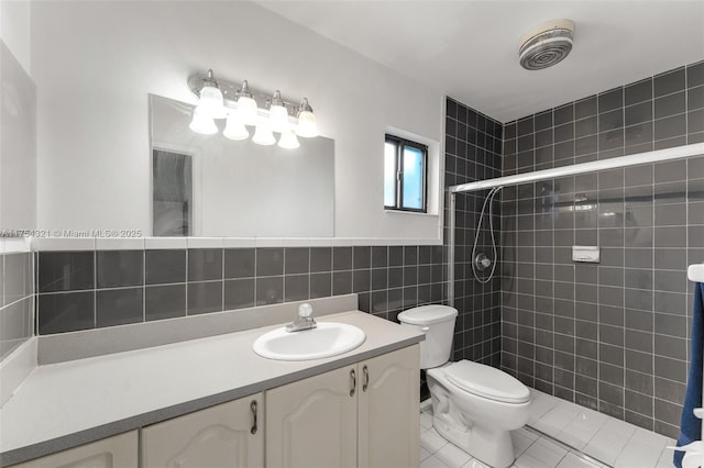 bathroom featuring tiled shower, toilet, tile patterned floors, vanity, and tile walls