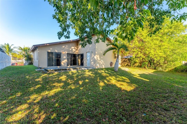 back of house featuring a lawn and stucco siding