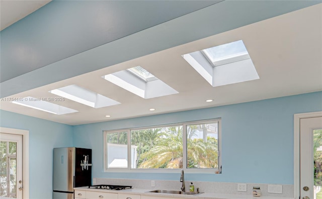 kitchen featuring freestanding refrigerator, cooktop, a sink, and recessed lighting