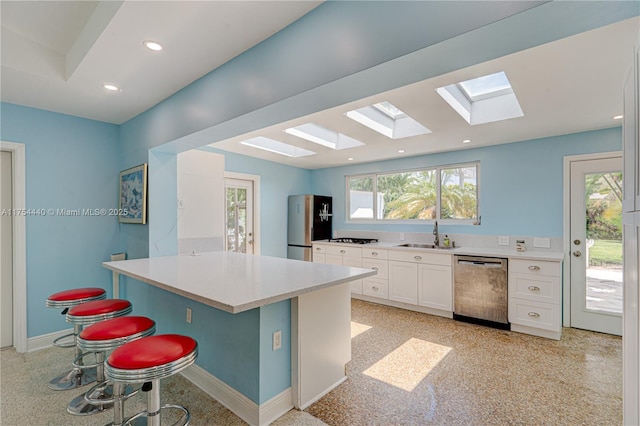 kitchen with recessed lighting, stainless steel appliances, a sink, a kitchen breakfast bar, and white cabinets