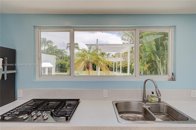 kitchen featuring stainless steel gas cooktop, light countertops, and a sink