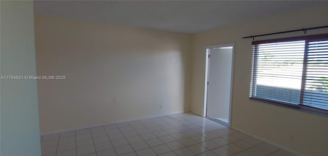 spare room with light tile patterned floors and baseboards