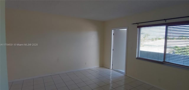 empty room with baseboards and light tile patterned flooring