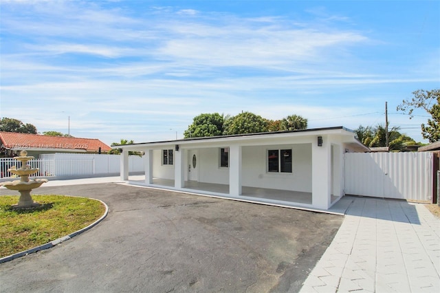 ranch-style home featuring a gate, a patio area, fence, and stucco siding