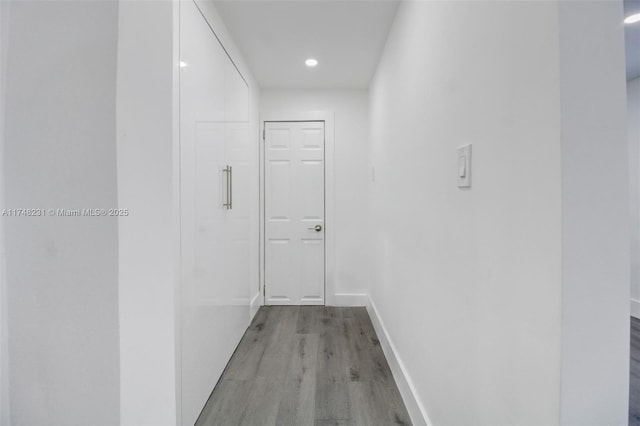 corridor with recessed lighting, wood finished floors, and baseboards