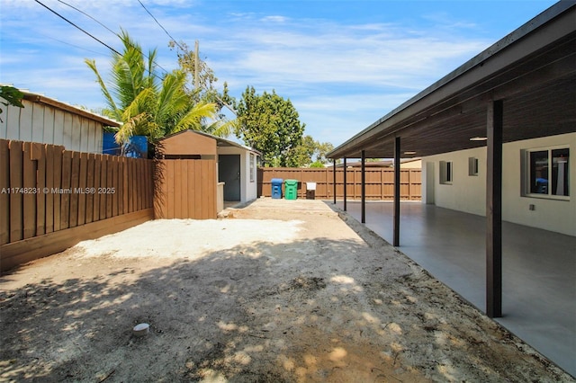 view of yard featuring an outbuilding, a patio, a shed, and a fenced backyard