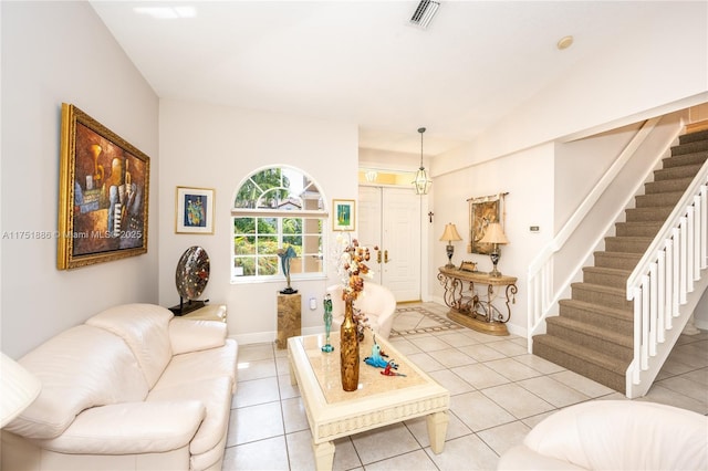 living area featuring light tile patterned floors, visible vents, baseboards, and stairs