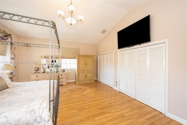 bedroom with visible vents, baseboards, lofted ceiling, light wood-style floors, and multiple closets