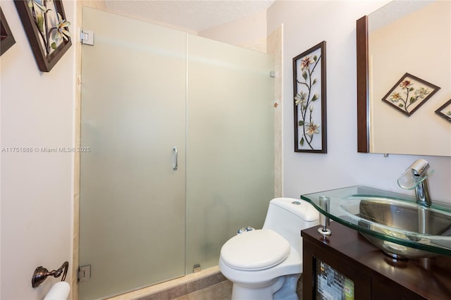 bathroom featuring a stall shower, vanity, toilet, and a textured ceiling