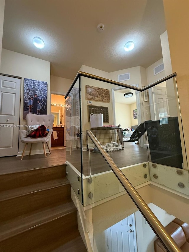 staircase with visible vents and wood finished floors