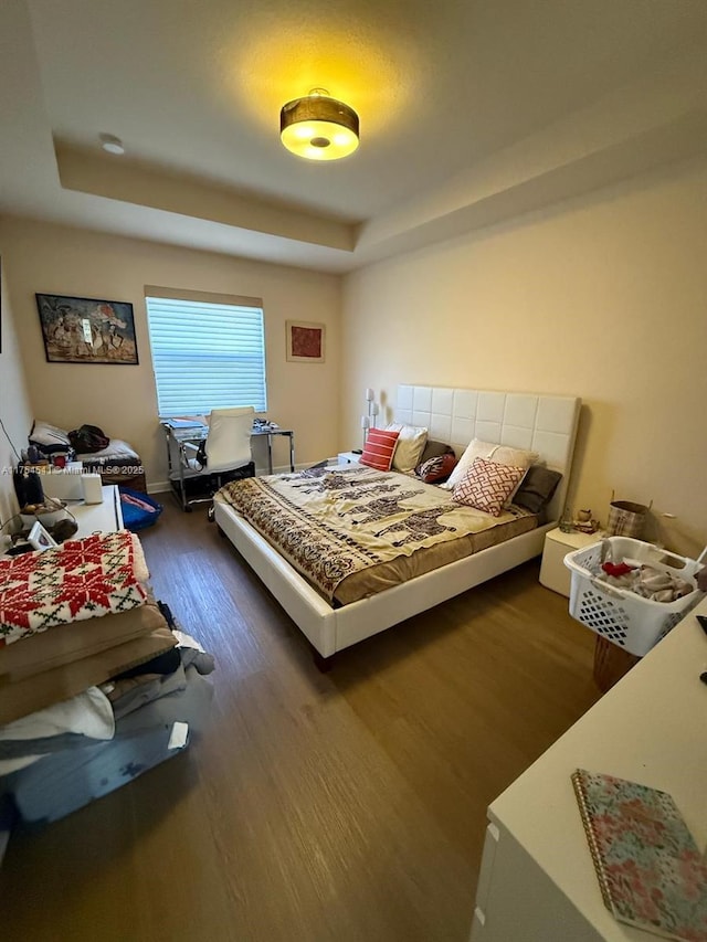 bedroom with dark wood-type flooring and a raised ceiling