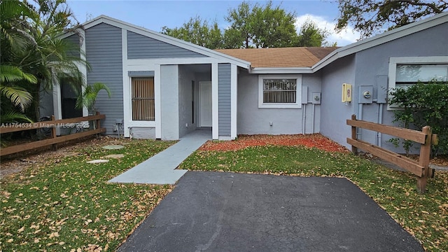 view of exterior entry with fence, a lawn, and stucco siding