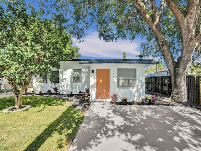 view of front of home featuring a front lawn, fence, and stucco siding