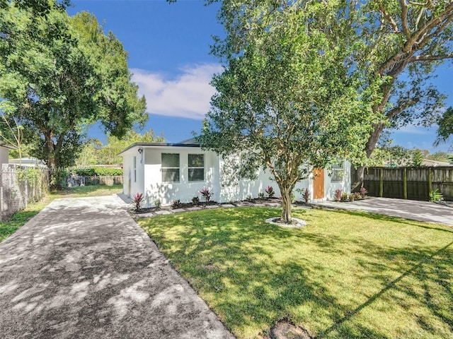 view of front of home with stucco siding, fence, and a front yard