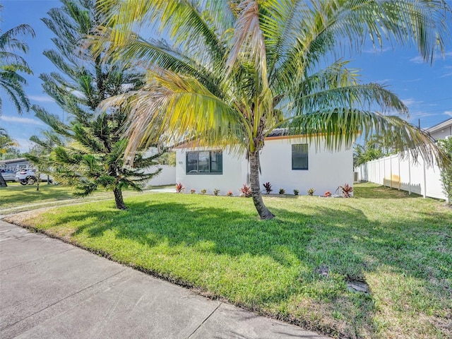 view of home's exterior with a lawn, fence, and stucco siding