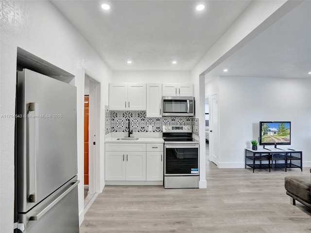 kitchen with light wood-style flooring, appliances with stainless steel finishes, decorative backsplash, and a sink