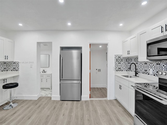 kitchen featuring light wood-style floors, tasteful backsplash, appliances with stainless steel finishes, and a sink