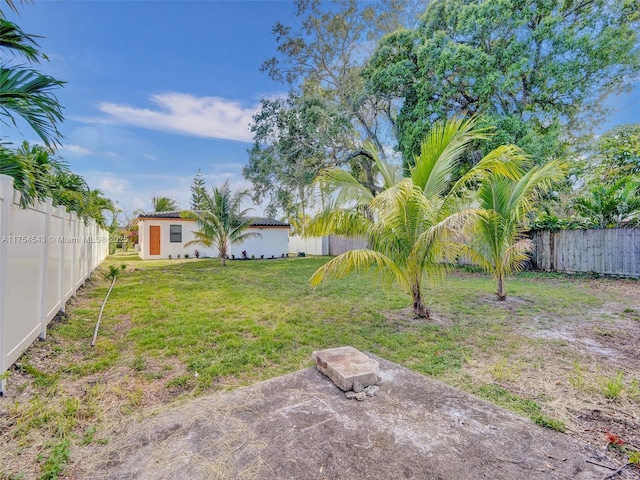 view of yard with a fenced backyard, an outdoor structure, and a patio