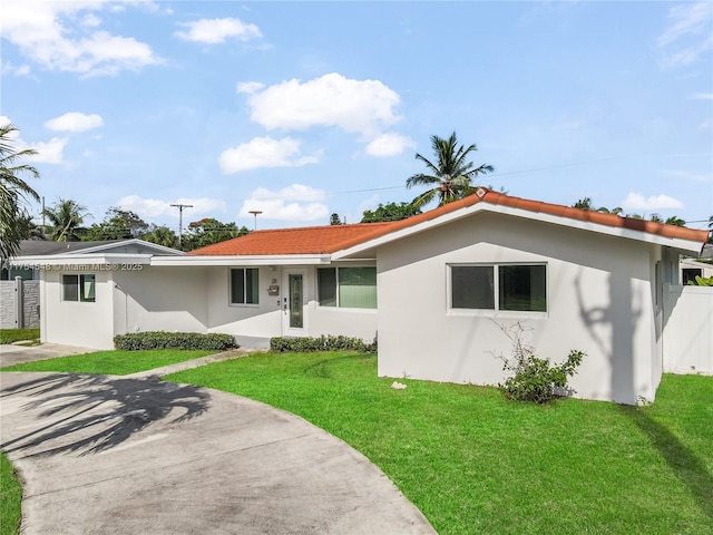 single story home featuring stucco siding, fence, and a front yard