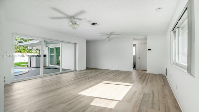 spare room with light wood-type flooring, visible vents, ceiling fan, and a textured ceiling