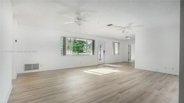 unfurnished room with a textured ceiling, light wood-type flooring, and visible vents