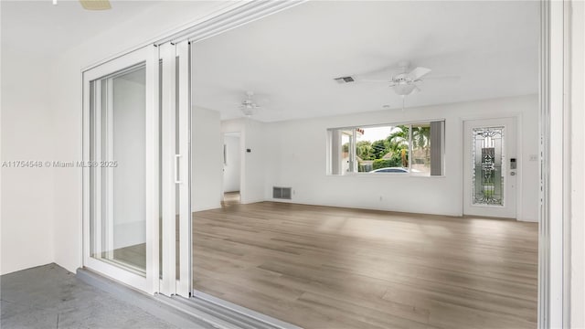 empty room with wood finished floors, visible vents, and a ceiling fan