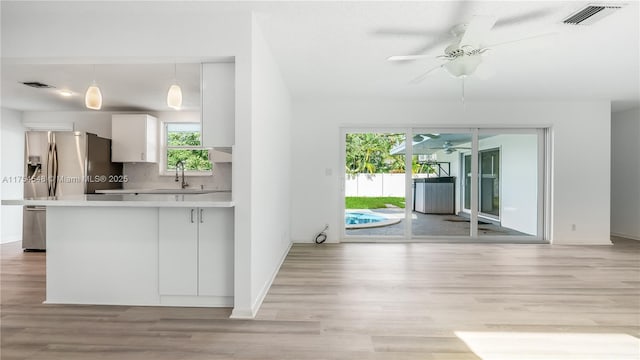 kitchen featuring a peninsula, light wood-style flooring, visible vents, and a sink