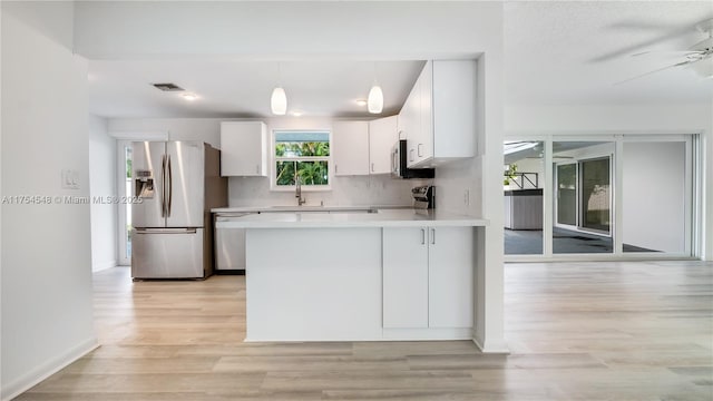 kitchen featuring stainless steel appliances, light countertops, a ceiling fan, white cabinetry, and a peninsula