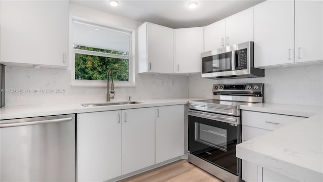 kitchen with appliances with stainless steel finishes, light countertops, a sink, and backsplash