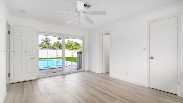 spare room with light wood-style floors, ceiling fan, visible vents, and baseboards