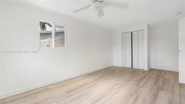 unfurnished bedroom featuring a ceiling fan, a closet, baseboards, and wood finished floors