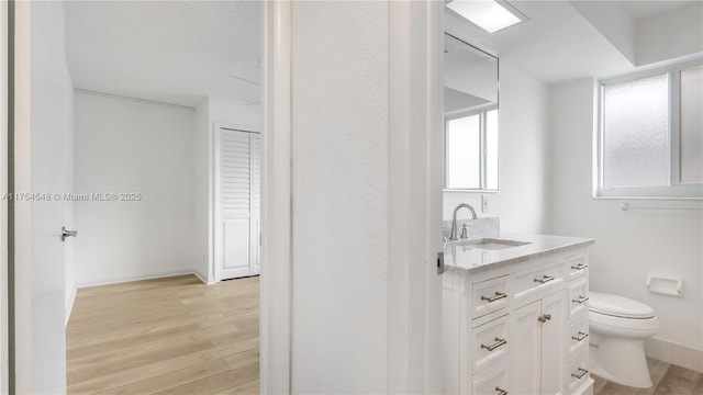 bathroom with toilet, baseboards, wood finished floors, and vanity